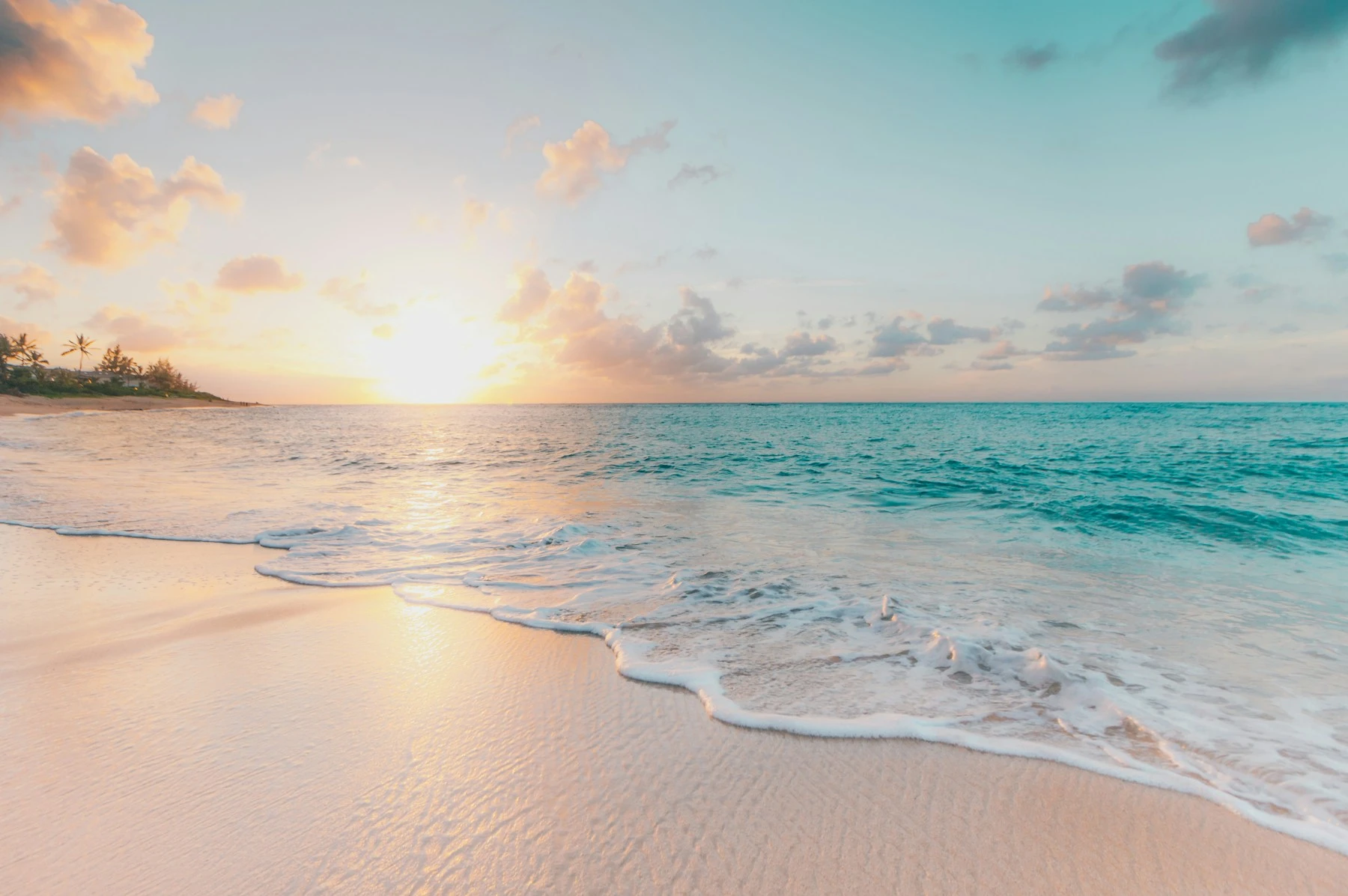 Pale sand and gentle turquoise surf in warm evening light